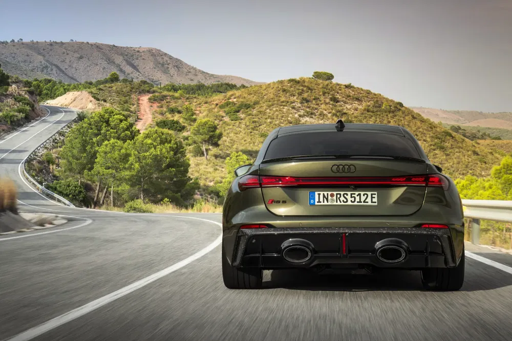 Groene Audi RS 5 op een kronkelende bergweg met prachtig uitzicht.