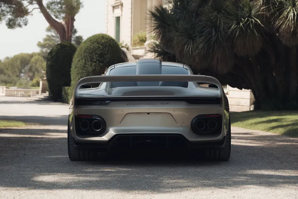 Vue arrière d'une Porsche 911 Mission X garée devant un manoir élégant.
