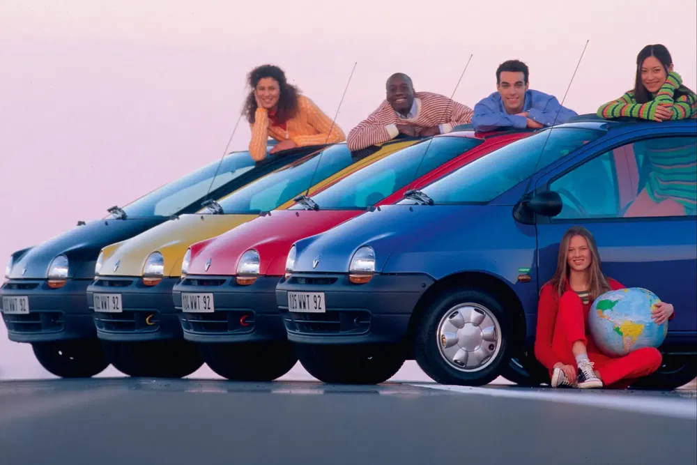 Cinq Renault Twingo de couleur vive alignées avec des personnes posant joyeusement dessus.