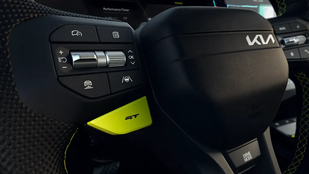 Volant de voiture Kia avec commandes intégrées et bouton jaune ST visible.