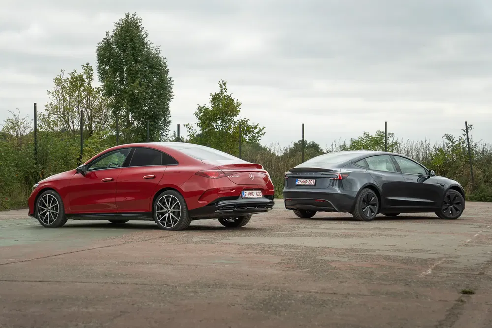 Mercedes CLA rouge et Tesla Model 3 gris garées en plein air, vue arrière.