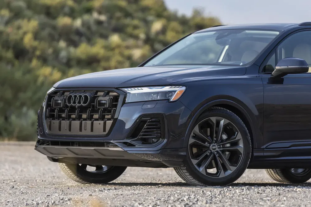 Audi Q7 stationnée sur une route, vue avant montrant la calandre et les phares distinctifs.
