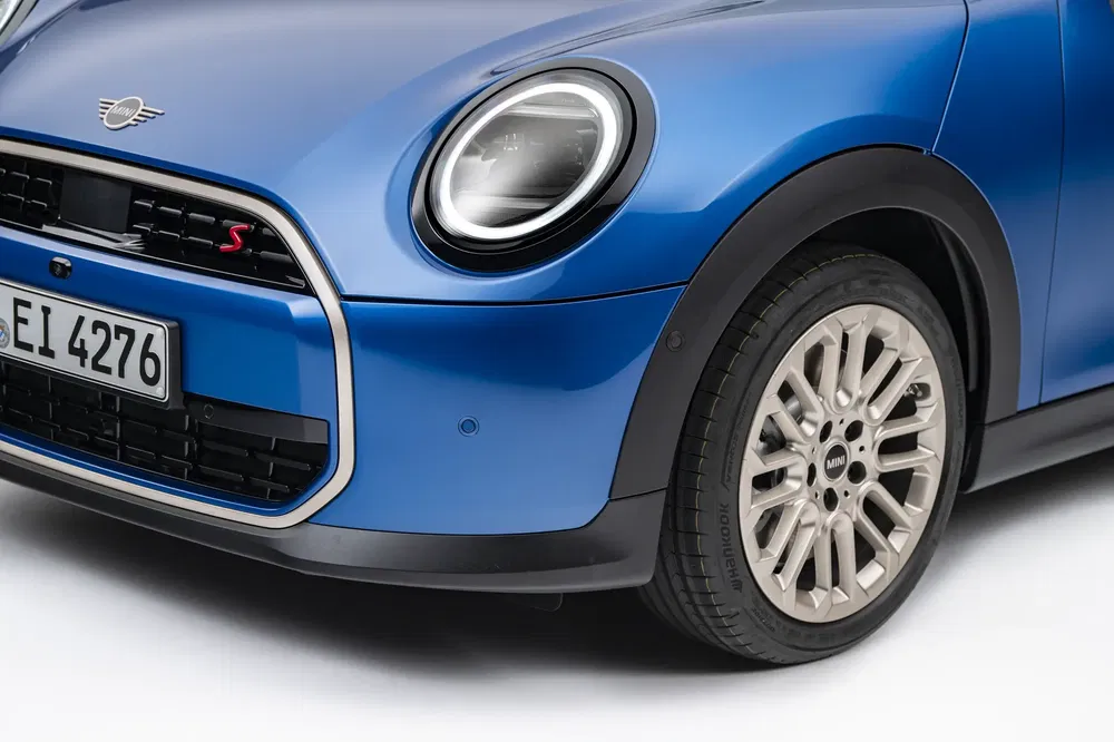 Vue avant d'une Mini Cooper bleue, soulignant le phare distinctif et la calandre moderne.