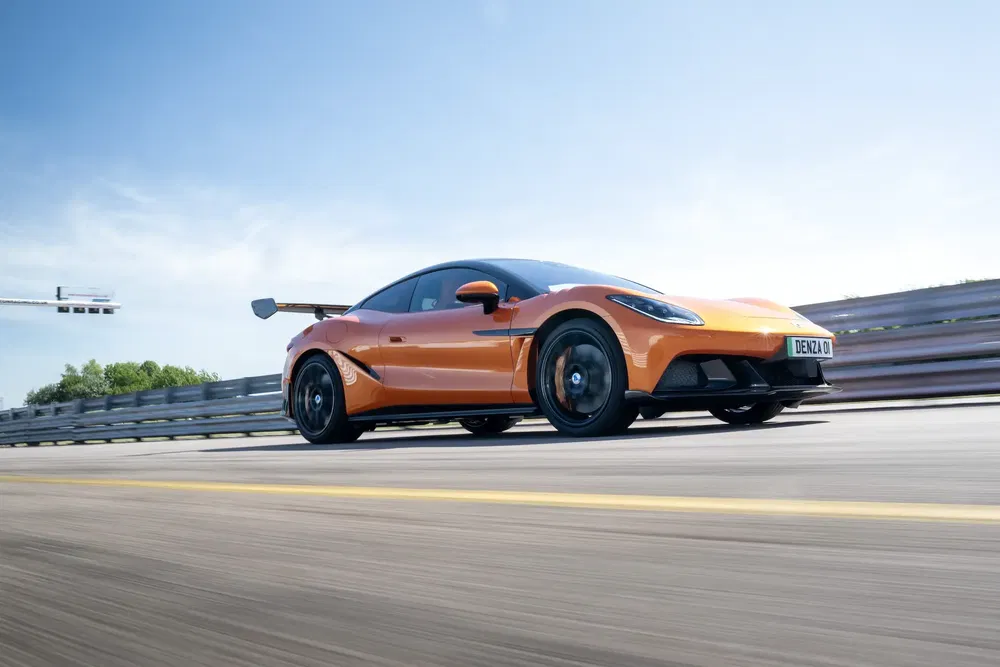 Voiture orange sportive sur circuit, probablement une supercar moderne avec aileron arrière.