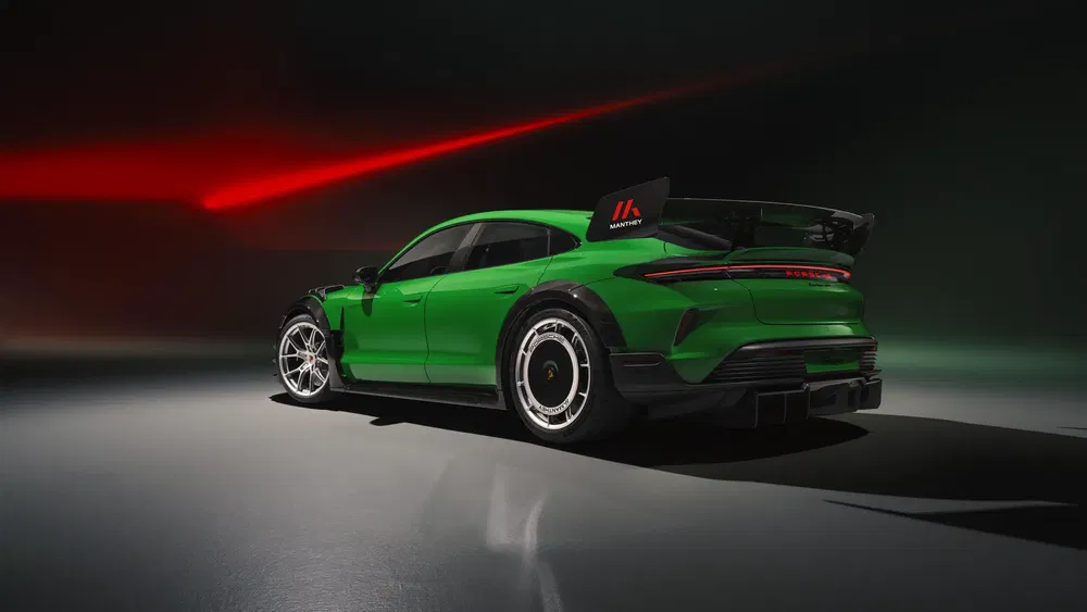 Porsche Taycan vert avec aileron arrière, éclairage dramatique rouge en arrière-plan.