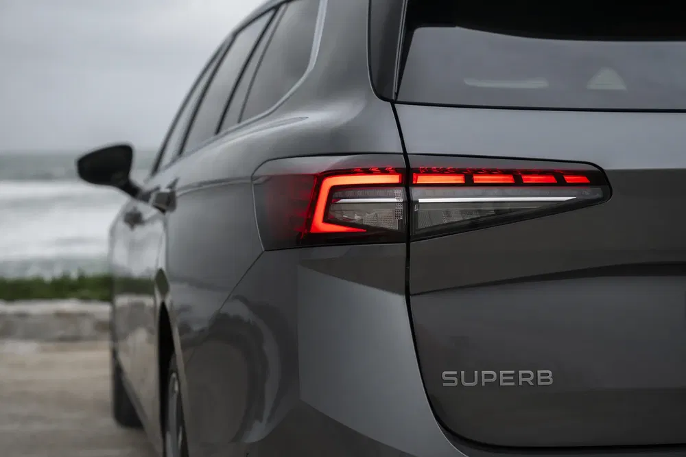 Vue arrière d'une Skoda Superb avec feux arrière LED allumés en bord de mer.