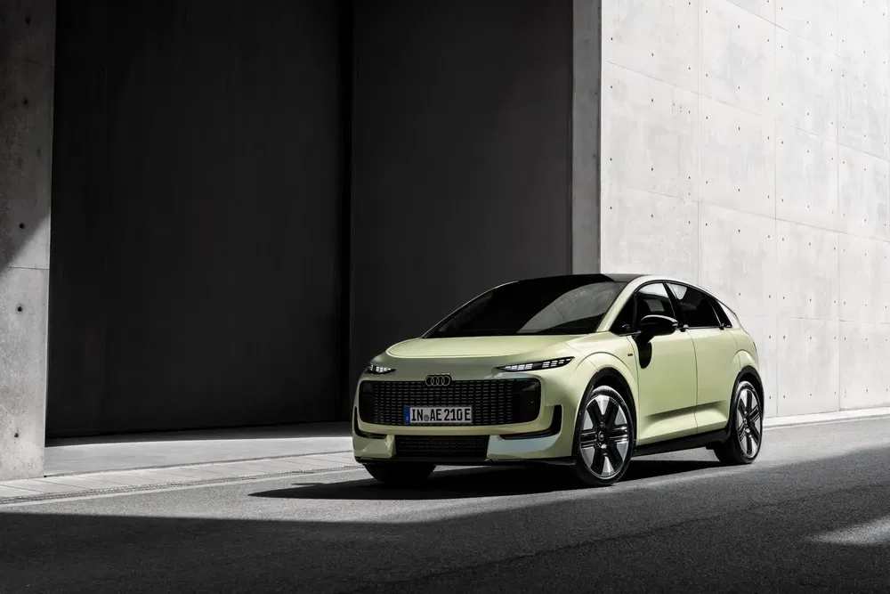 Audi électrique moderne, teinte verte, sur route urbaine aux murs en béton.