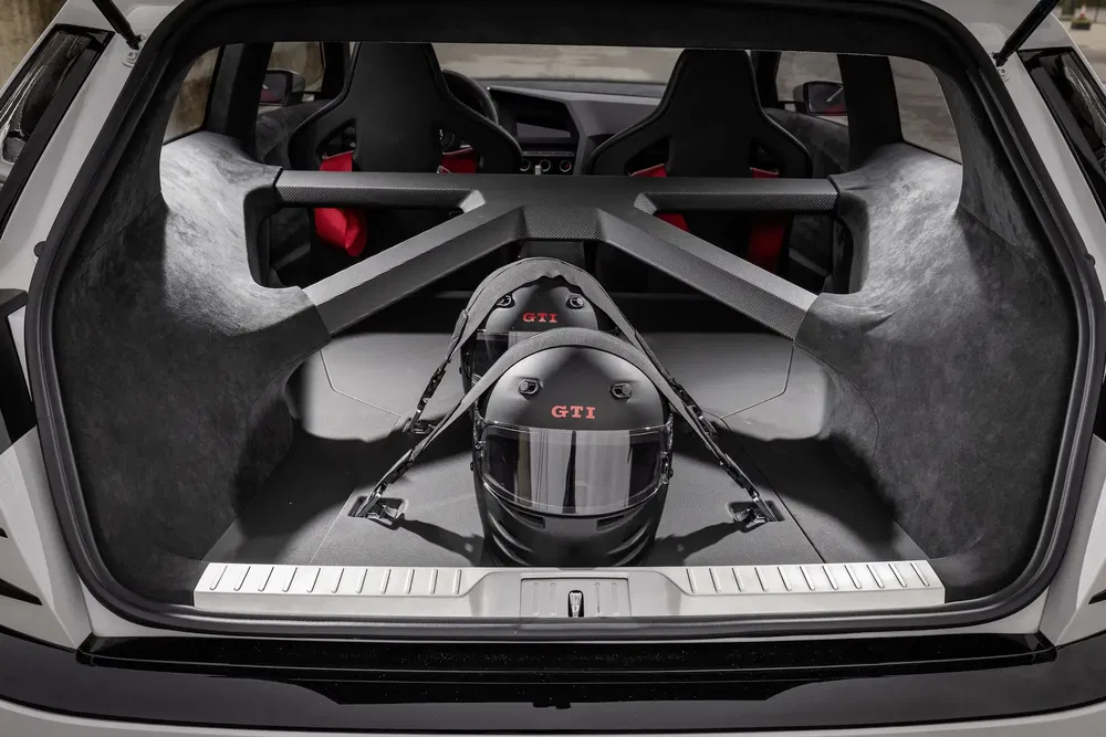 Intérieur de coffret Volkswagen GTI avec deux casques de course, sièges sport visibles à l'arrière.