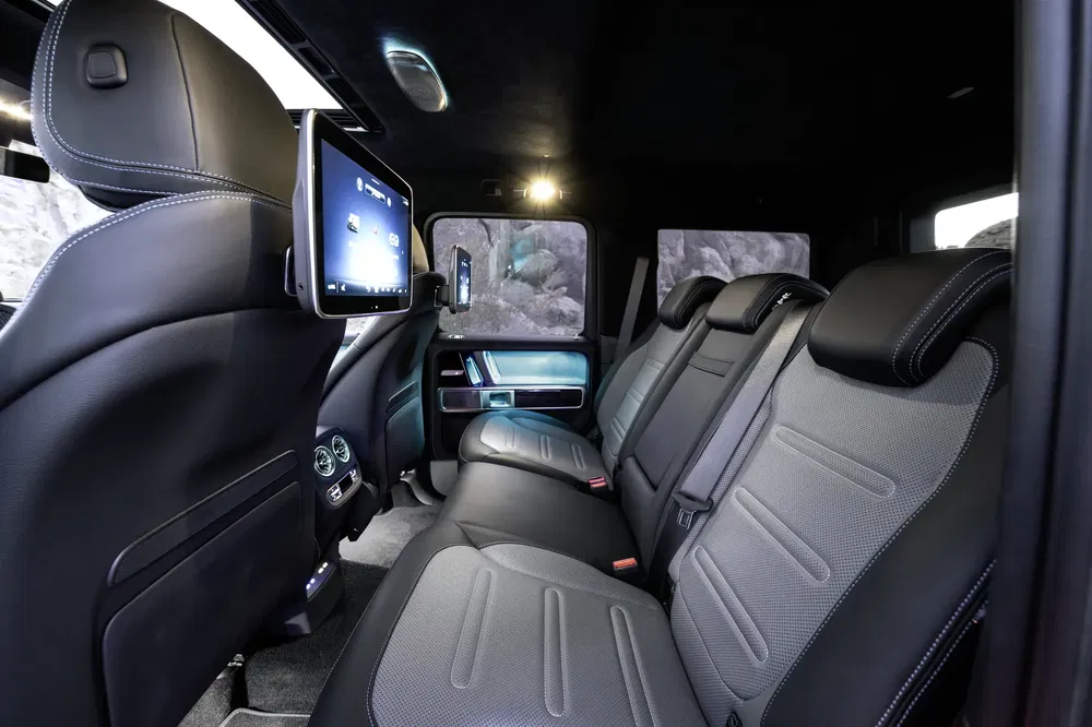 Intérieur du SUV Mercedes-Benz Classe G, sièges en cuir noir, écran multimédia arrière visible.