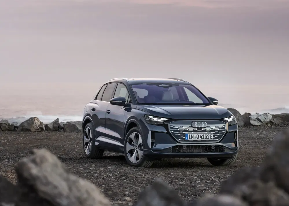 Audi Q4 e-tron garé sur un terrain rocheux avec ciel pastel en arrière-plan.