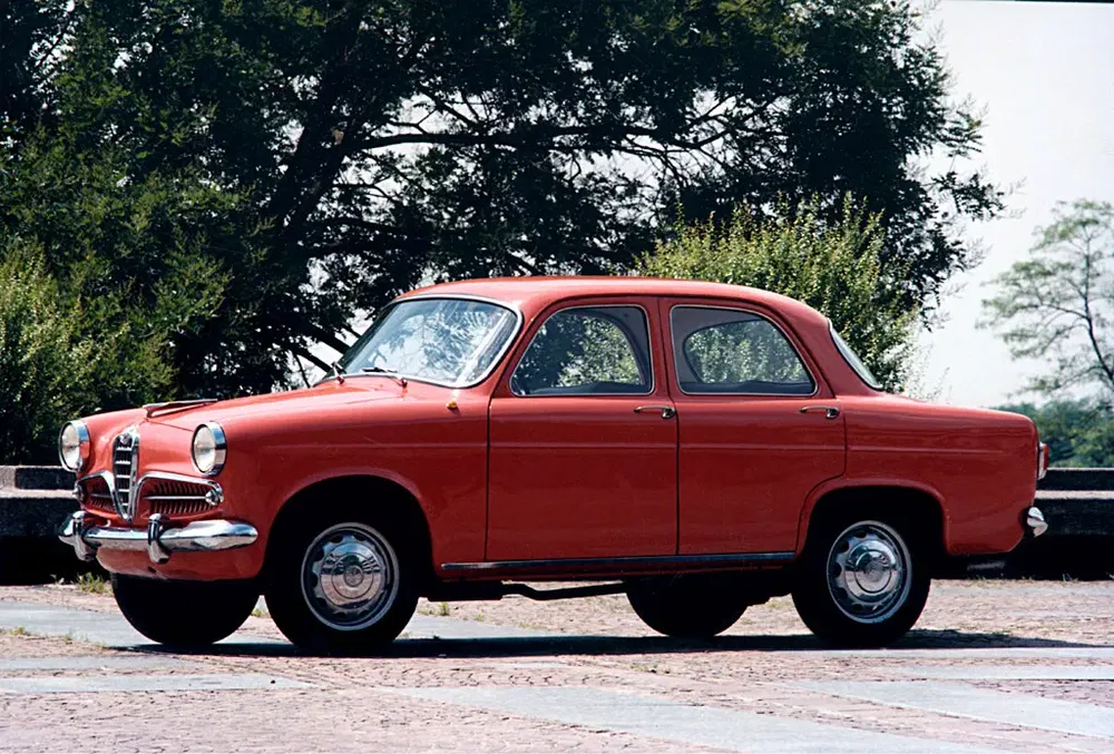 Berline Alfa Romeo classique rouge stationnée près d'arbres, allure vintage et élégante.