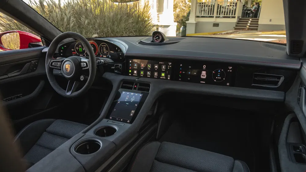 Intérieur de la Porsche Taycan avec tableau de bord numérique et sièges en cuir noir.