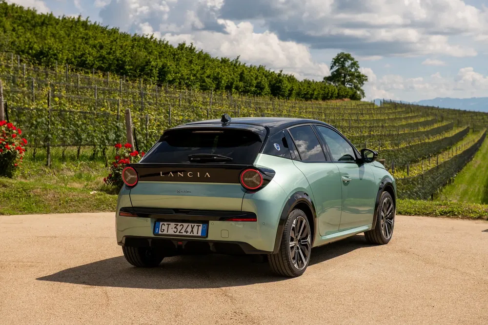 Lancia Ypsilon 2023 op een landweg omgeven door groene wijngaarden.
