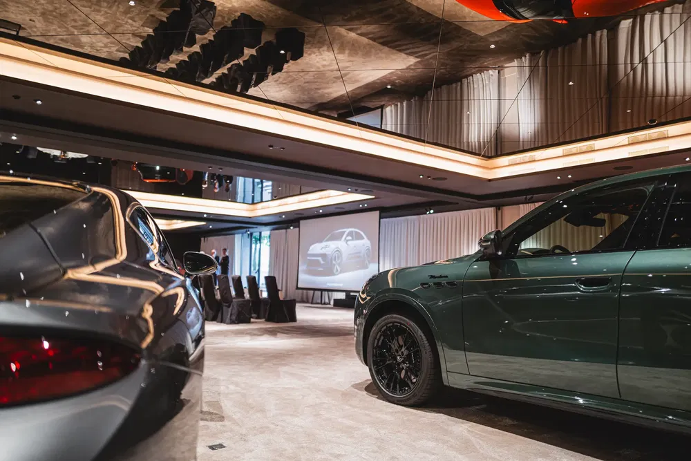 Deux voitures de luxe modernes dans une salle d'exposition élégante avec écran de projection.