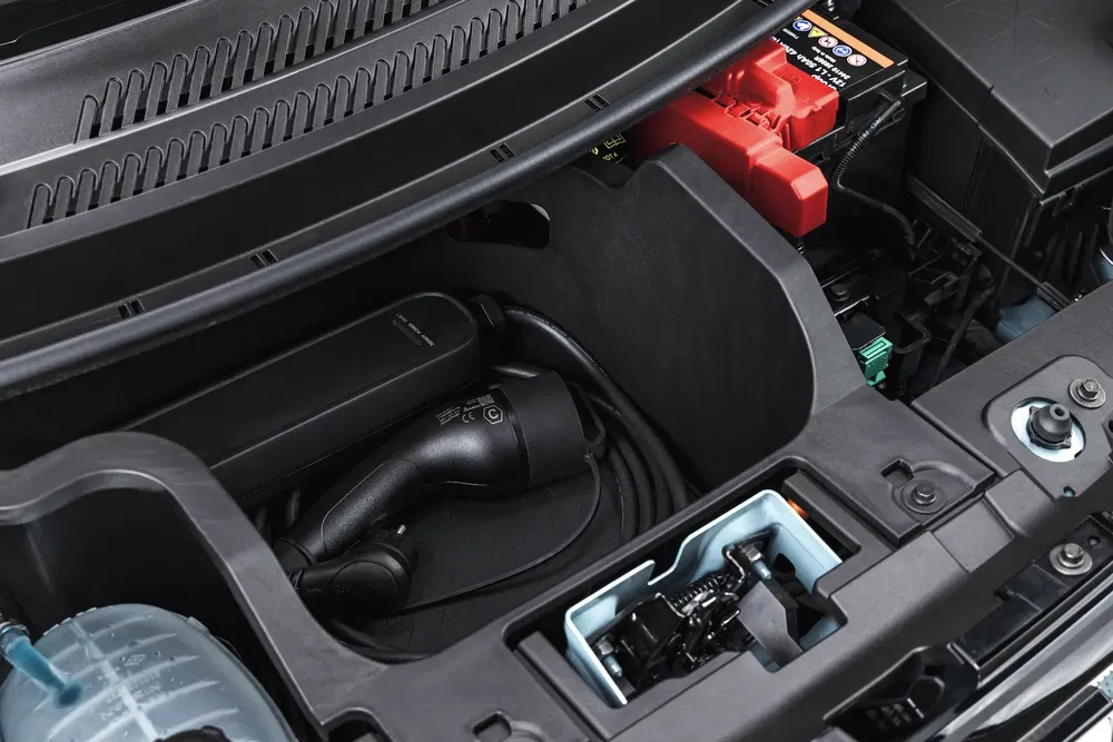 {"fr":"Coffre avant de véhicule électrique avec chargeur et batterie visibles.","nl":"Voorste bagageruimte van elektrische auto met oplaadkabel en accubank zichtbaar."}