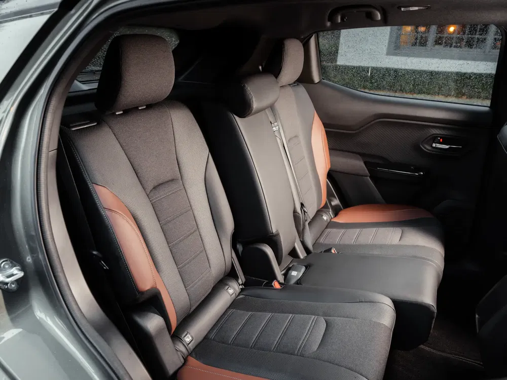 Achterbank van een auto met zwarte stoffen bekleding en bruine accenten.