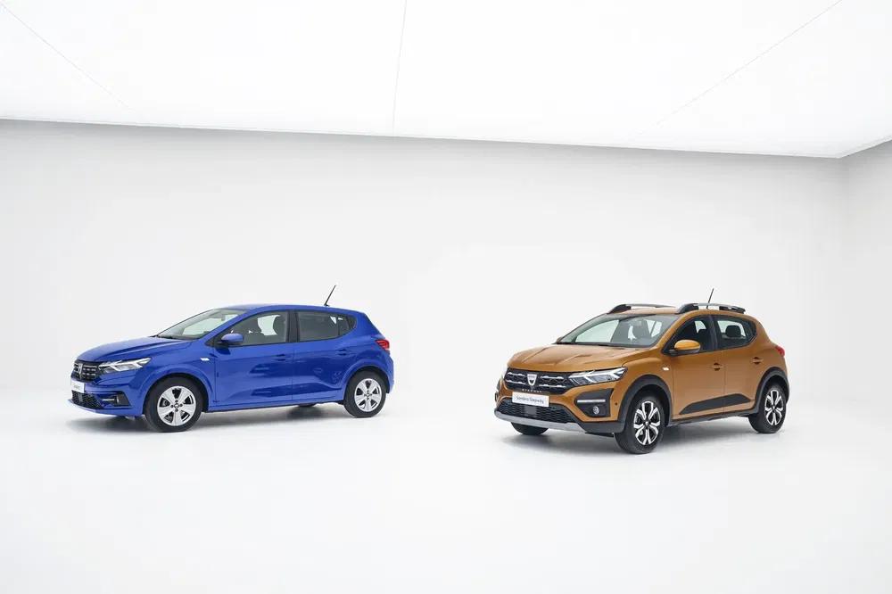 Twee Dacia-modellen, een blauwe Sandero en een bruine Sandero Stepway, in witte studio.