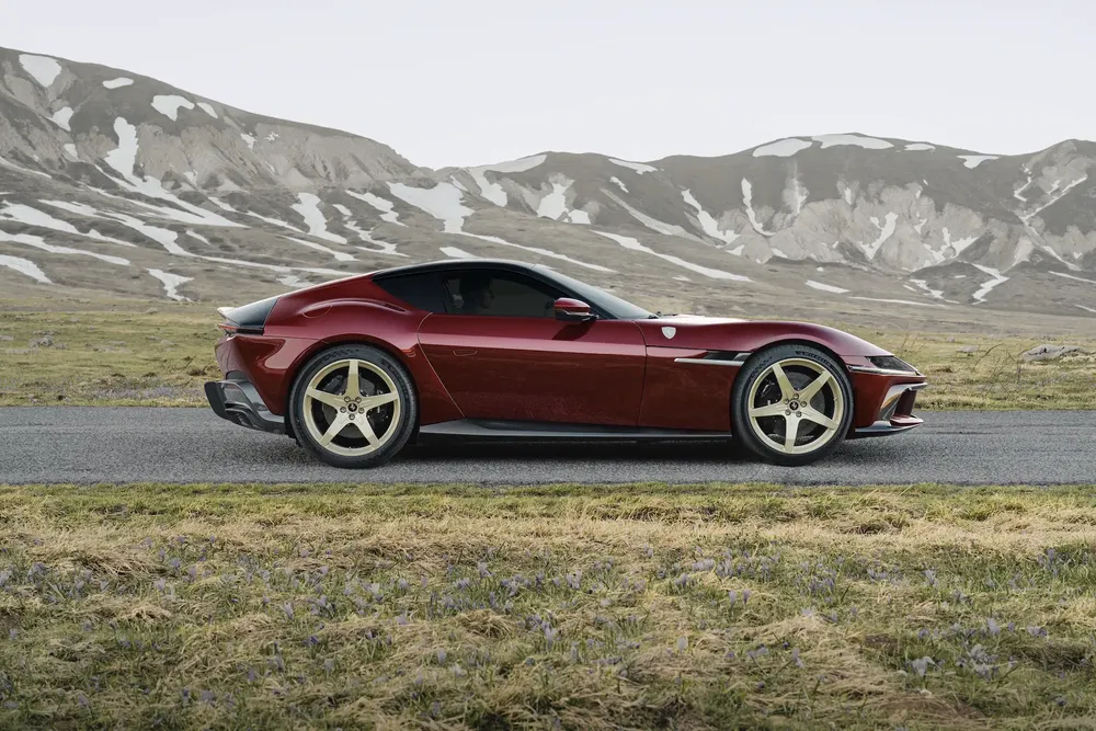 Ferrari Roma rouge garée devant un paysage montagneux, route de campagne paisible.