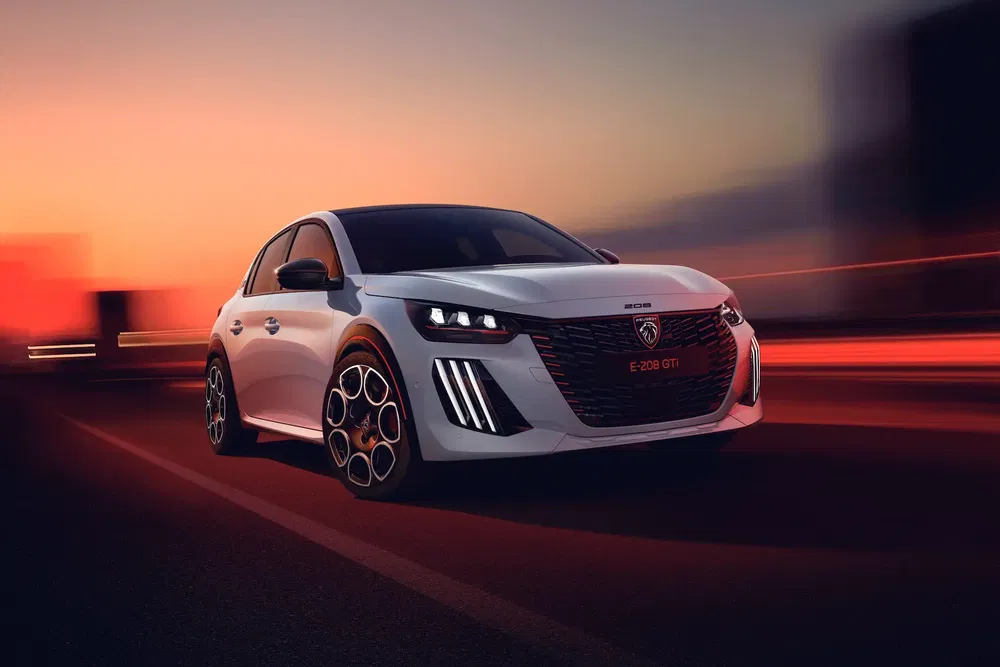 Voiture Peugeot E-208 GTi blanche au crépuscule sur route dégagée, design sportif moderne.