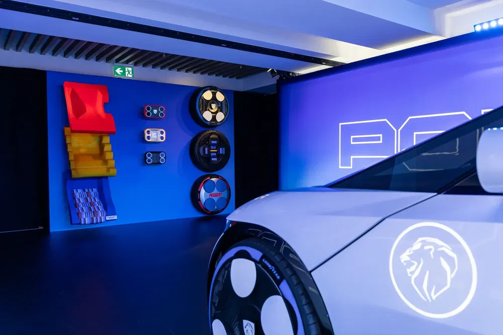 Exposition de roue avant d'une voiture Peugeot dans une salle colorée et moderne.