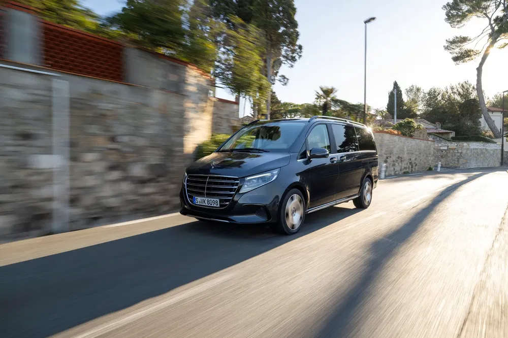 {"fr":"Mercedes-Benz Classe V roulant sur une route bordée d'arbres, éclairage en fin de journée.","nl":"Mercedes-Benz V-Klasse rijdt op een met bomen omzoomde weg, avondlicht."}
