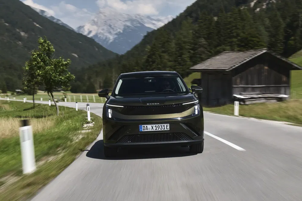 Skoda Enyaq rijdt op een bergweg omgeven door groene alpenlandschappen.