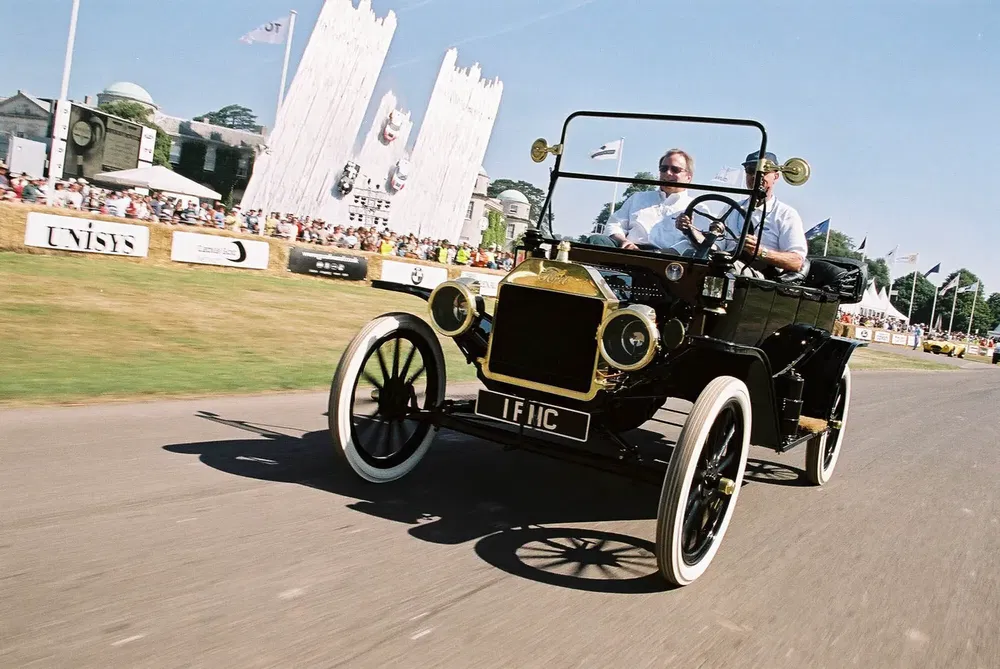 Ancienne voiture Ford Model T noire roulant à un événement en plein air.