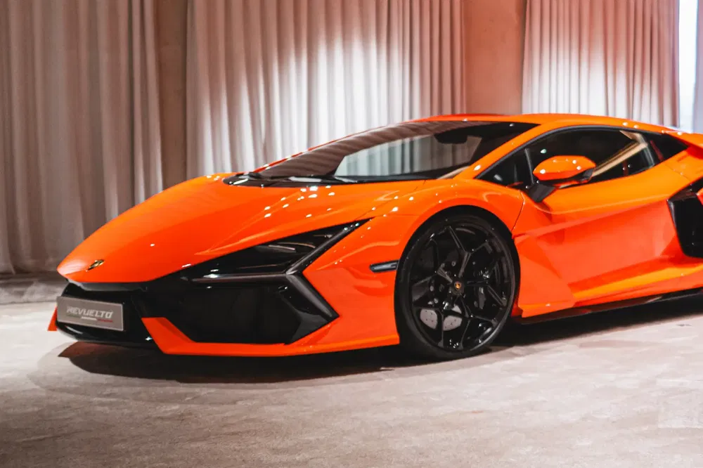 Lamborghini Revuelto orange vif dans un showroom luxueux, design agressif et élégant.