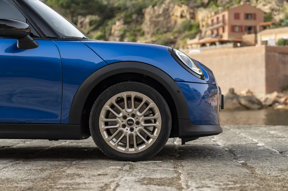 Demi-profil avant d'une Mini Countryman bleue près de paysages côtiers rocheux.