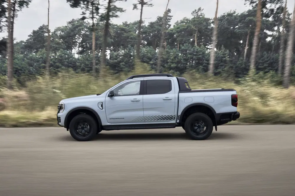 Ford Ranger blanc roulant sur une route bordée d'arbres.