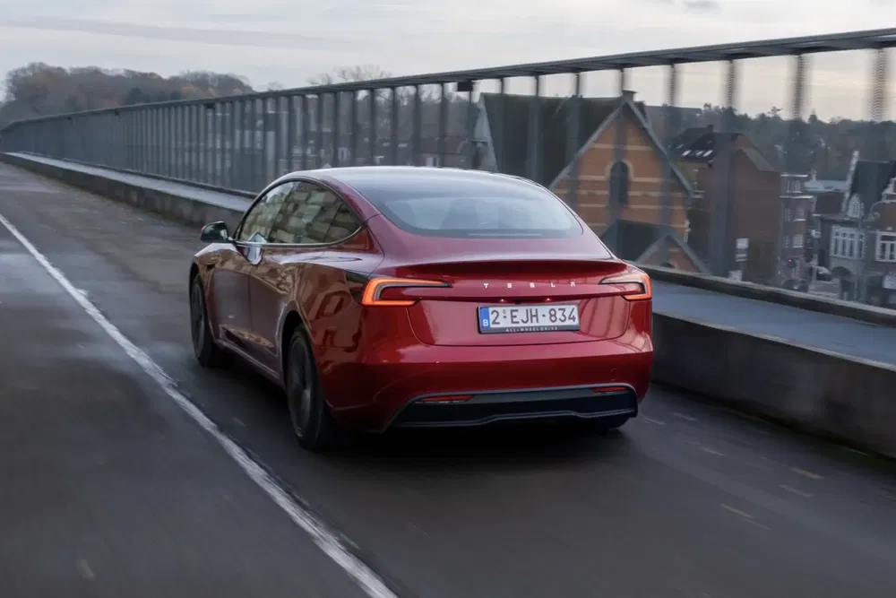Tesla rouge sur un pont, vue arrière, conduite en milieu urbain.