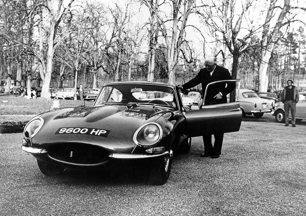 Jaguar E-Type sportwagen met kenteken 9600 HP, man opent de deur.
