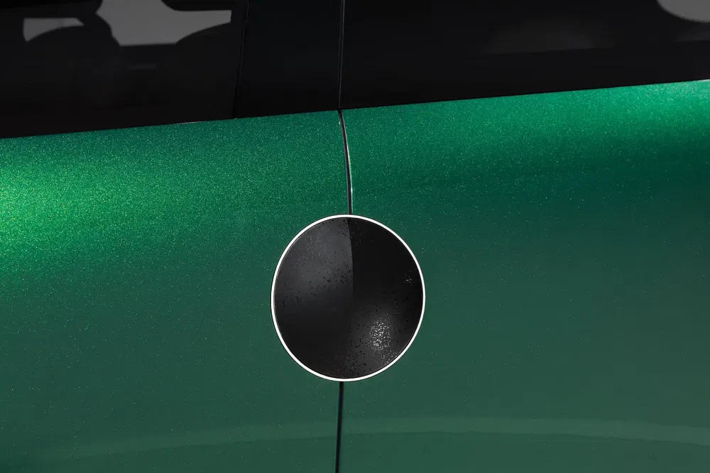 Portière latérale verte de la MINI Cooper SE avec poignée circulaire distinctive.