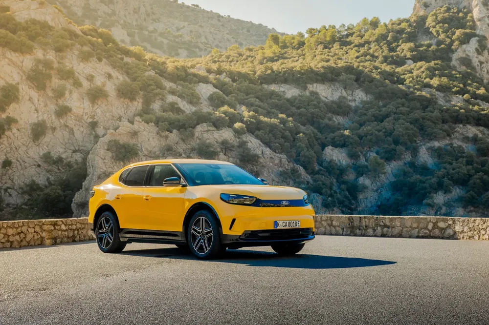 Gele elektrische auto op bergweg met schilderachtig landschap.