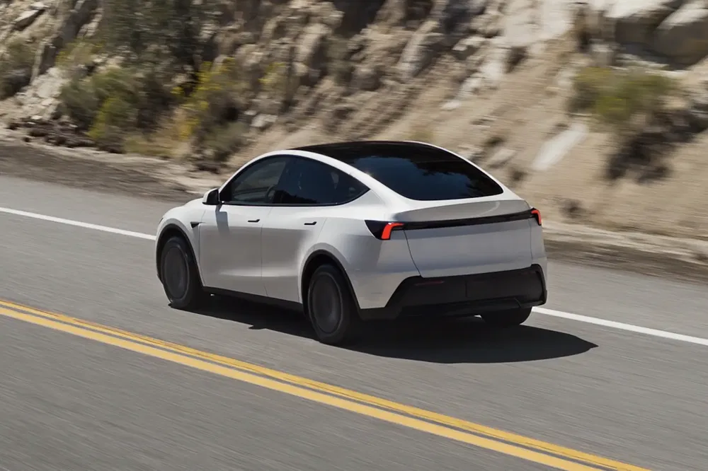 {"fr":"Tesla Model Y blanche roulant sur route de montagne, vue de arrière latérale.","nl":"Witte Tesla Model Y rijdt op bergweg, gezien vanaf de achterkant."}