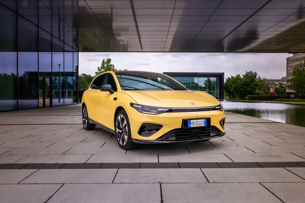 Nouvelle Volkswagen ID.7 jaune garée devant un bâtiment moderne et lisse.