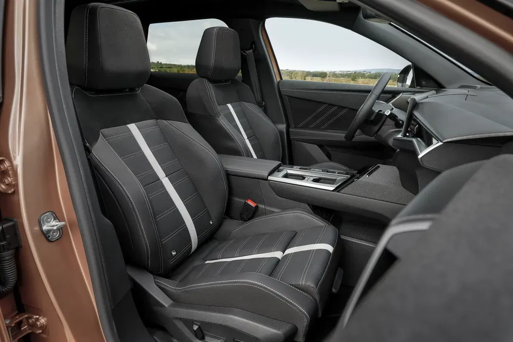 Intérieur du véhicule avec sièges Peugeot modernes et élégants en tissu noir à rayures.