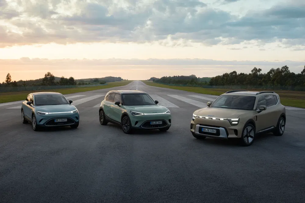 Trois voitures Smart électriques modernes alignées sur une piste au lever du soleil.