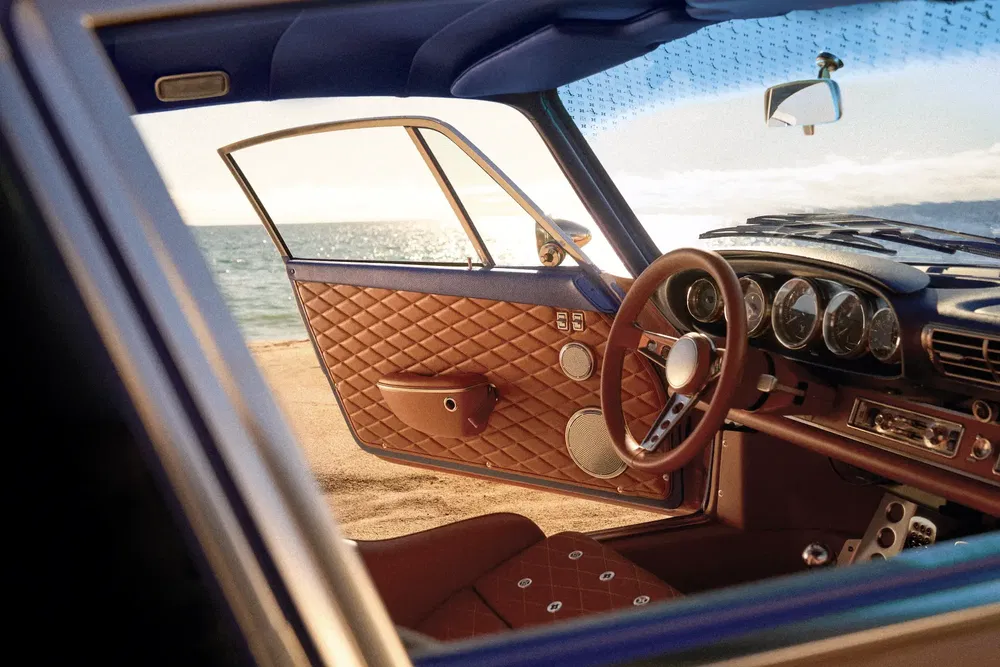 Intérieur d'une voiture de luxe avec garniture en cuir marron, vue sur l'océan.