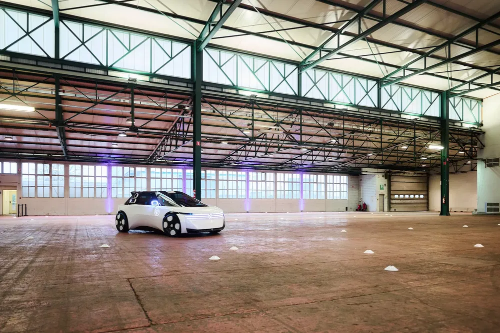 Prototype de voiture autonome blanche dans un entrepôt spacieux et bien éclairé.