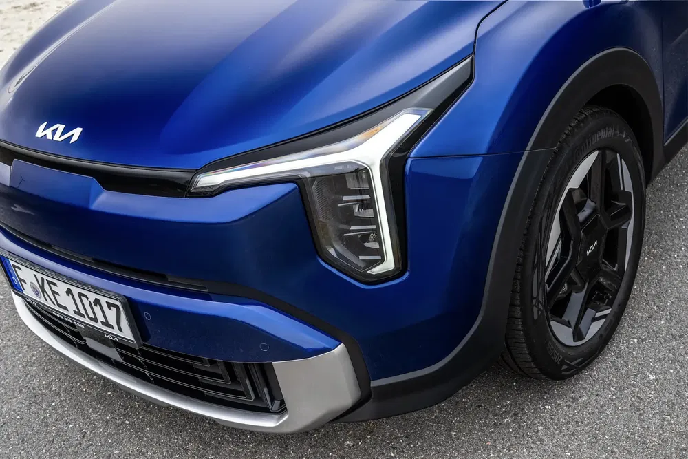 Blauwe Kia auto met kenmerkende LED-koplampen en stijlvolle zwarte velgen.