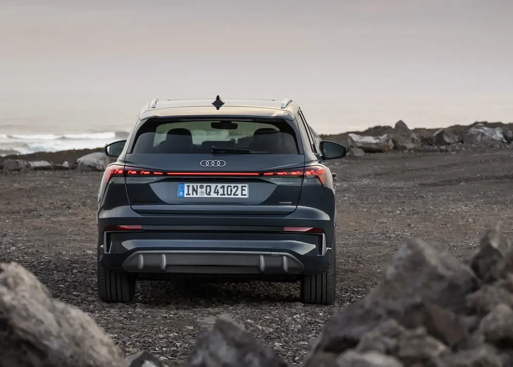 Arrière de l'Audi Q4 e-tron sur un terrain rocheux au bord de la mer.