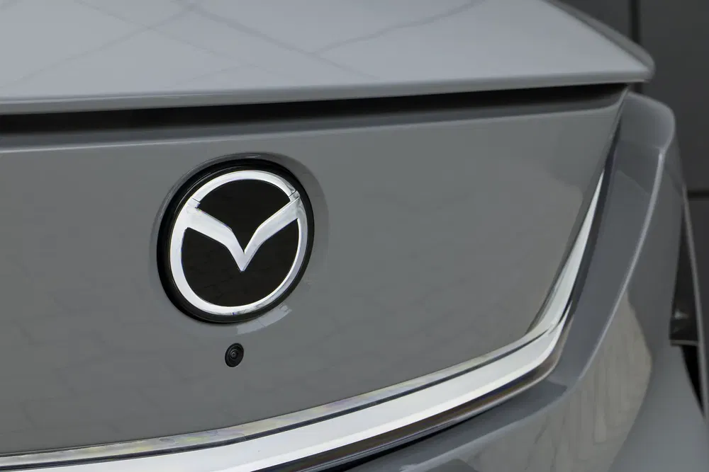 Logo Mazda sur hayon arrière gris, vue rapprochée, design moderne et élégant.