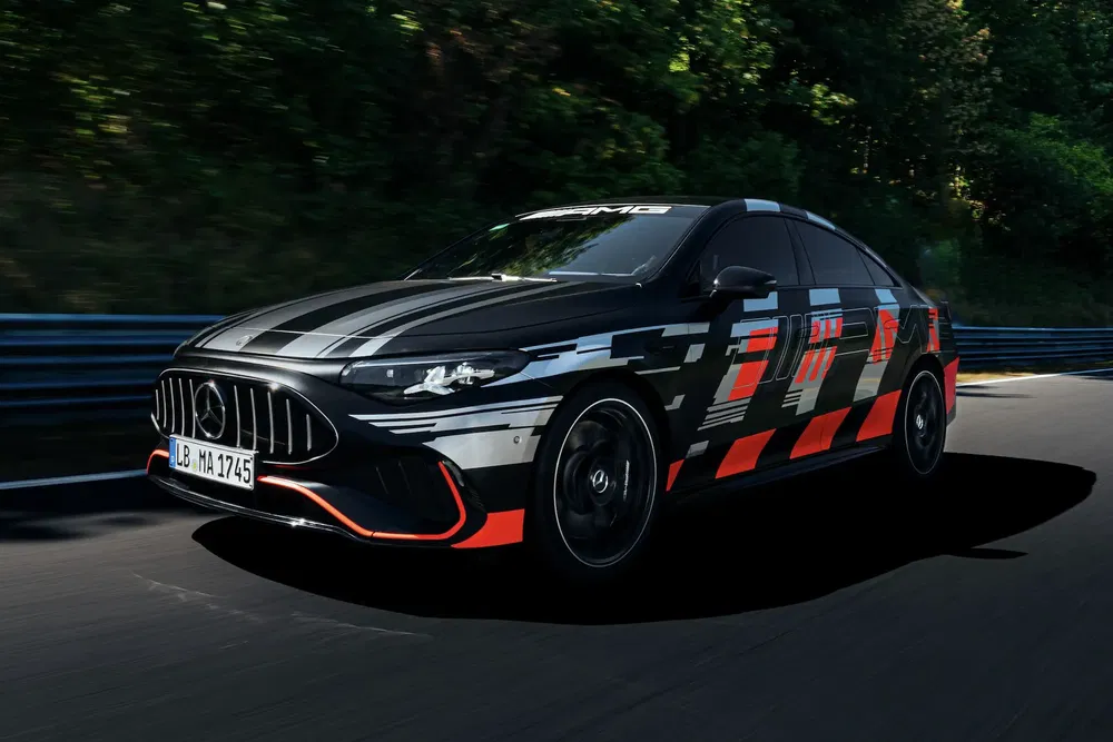 Mercedes-AMG sedan in camouflage op circuit, met opvallende oranje en grijze accenten.