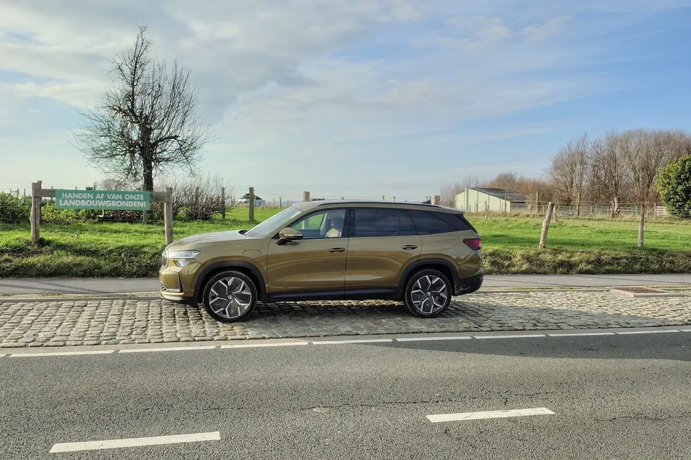 SUV bronze moderne stationné sur une route pavée, paysage champêtre à l'arrière-plan.