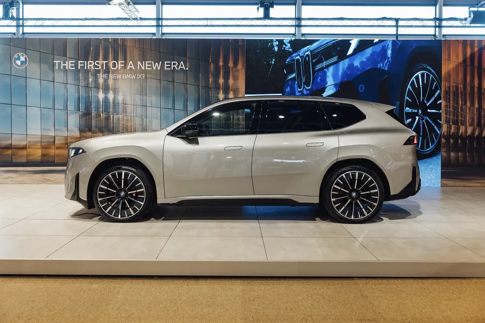 BMW iX3 2023 gris dans un showroom moderne avec affiches en arrière-plan.