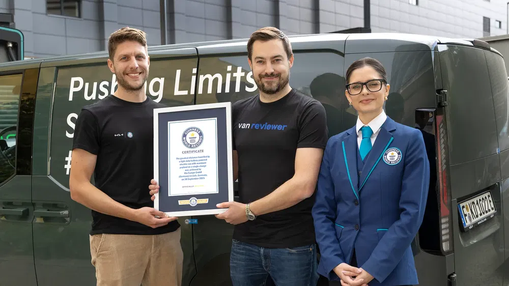 Trois personnes posant devant un van, tenant un certificat de record Guinness.