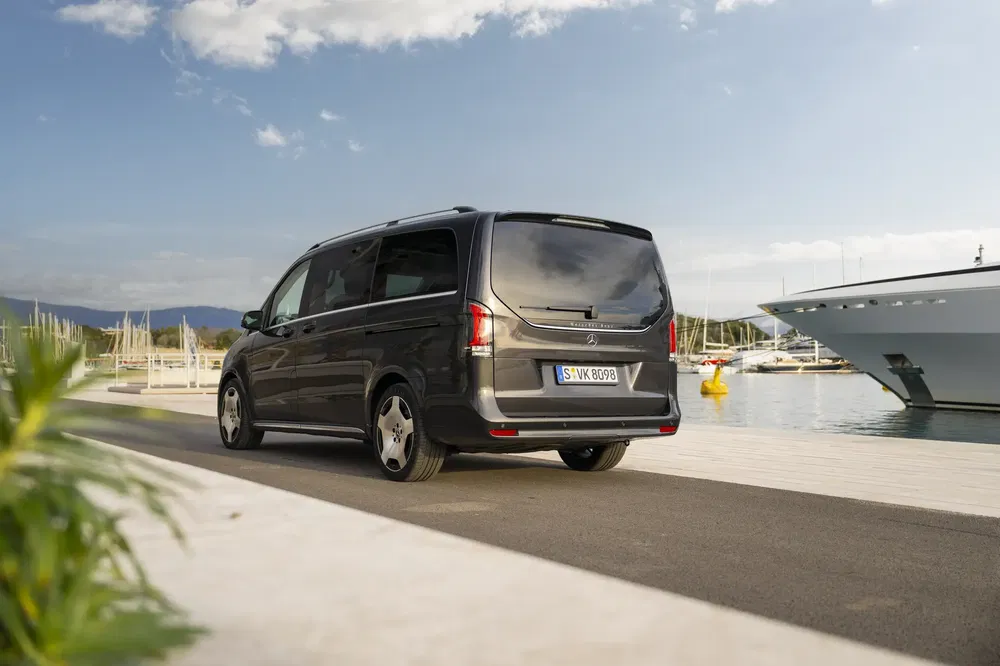 Grijze Mercedes-Benz V-Class busje geparkeerd bij een moderne jachthaven.