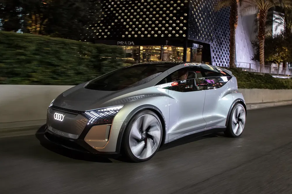 Elektrische Audi conceptauto rijdt 's nachts voor verlichte Prada-winkel.