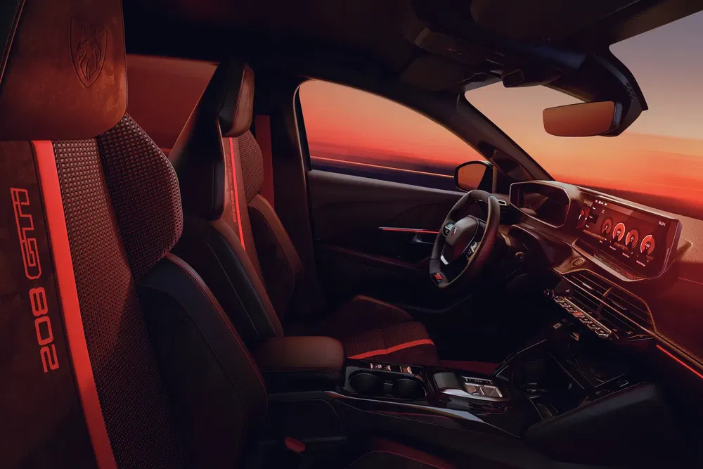 Intérieur moderne de la Peugeot 208 GTi au coucher du soleil, volant et tableau de bord numériques.